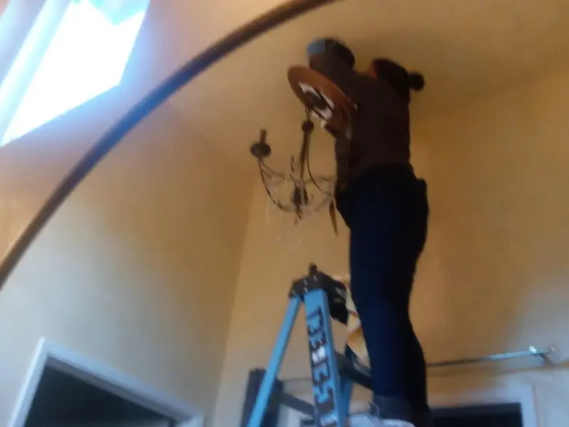 Electrician installing a chandelier in a Brooksville residence